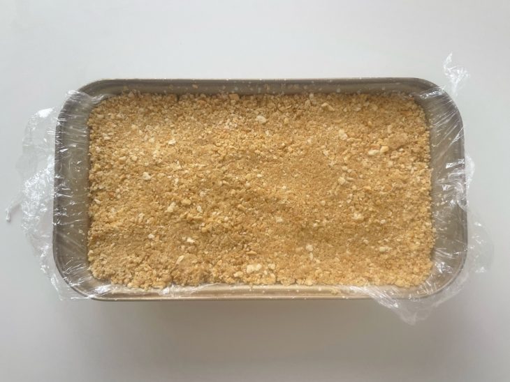 Farofa sendo pressionada sobre o creme já firme.