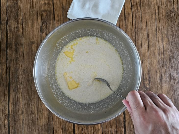 Um recipiente contendo tapioca granulada, manteiga e leite quente.