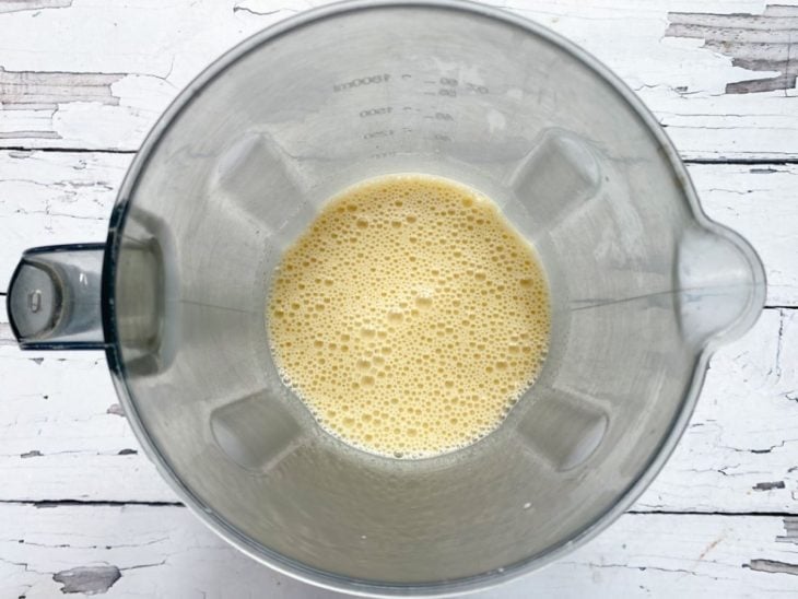 Um liquidificador com a mistura de ovos, leite de coco, óleo, açúcar e goma de tapioca.