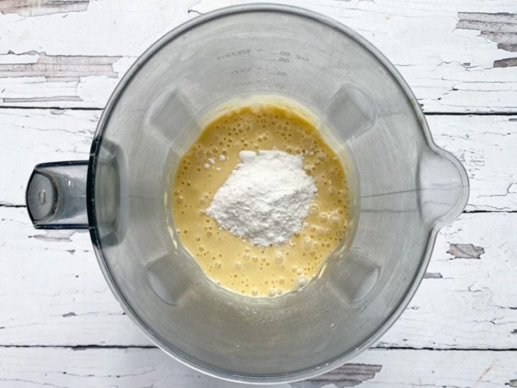 Um liquidificador com a mistura de ovos, leite de coco, óleo, açúcar, goma de tapioca, farinha e fermento.