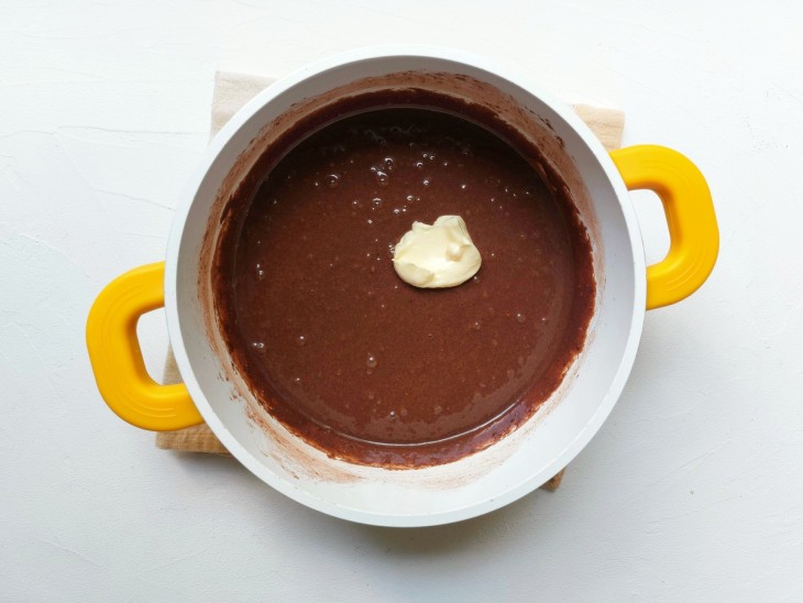 Uma panela com a mistura de leite condensado e manteiga, chocolate em pó.