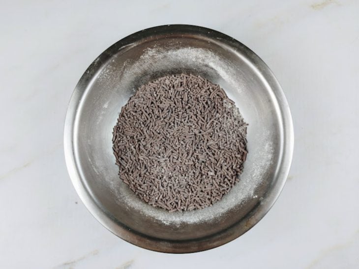 Tigela de alumínio com granulado misturado com farinha de trigo.
