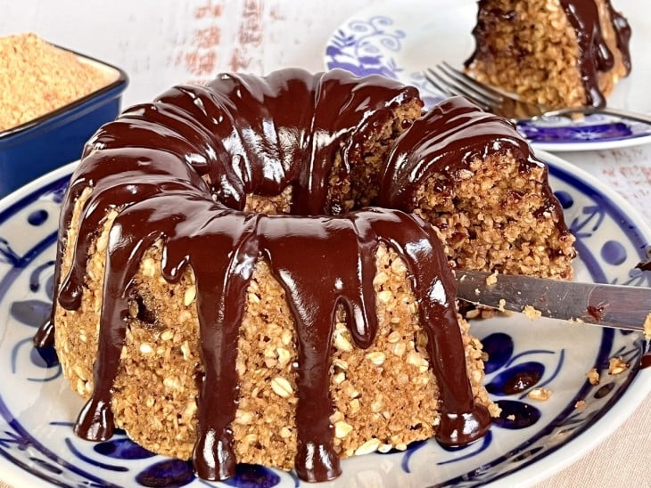 Bolo funcional de amendoim com cobertura de chocolate com pedaço cortado.