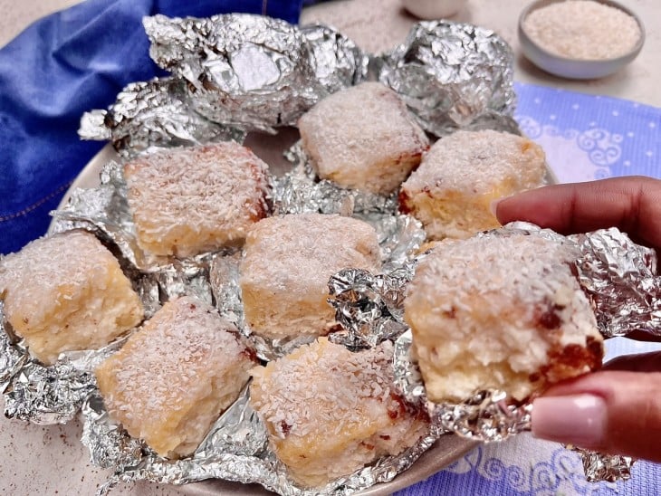 Um prato contendo pedaços de bolo gelado de coco.