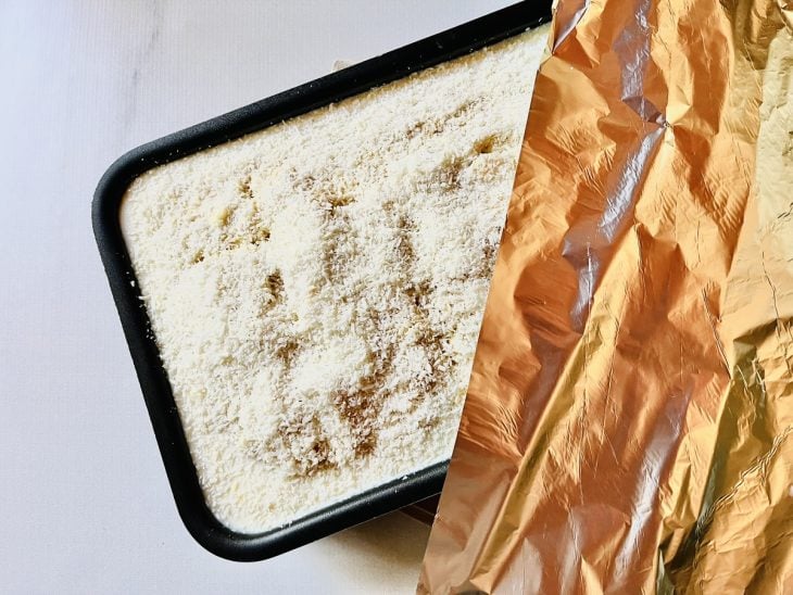 Calda despejada e coco polvilhado sobre o bolo.