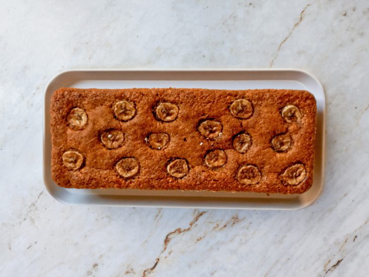 Bolo desenformado sobre um prato retangular branco.