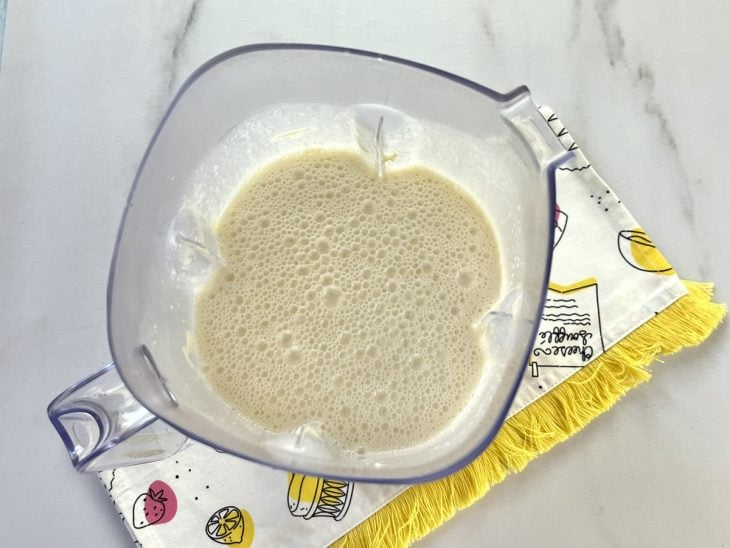 Um liquidificador contendo a mistura de ovos, manteiga, leite, açúcar, sal e farinha de trigo.