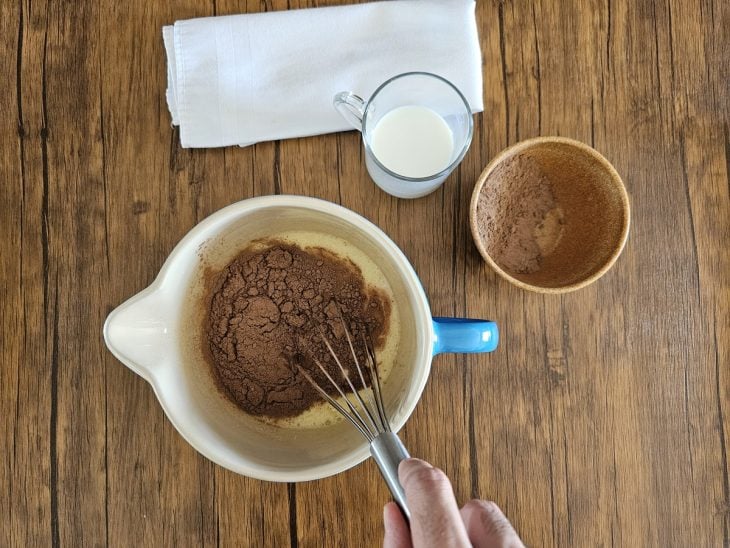 Uma tigela contendo a mistura de ovos, açúcar, óleo, leite e chocolate em pó