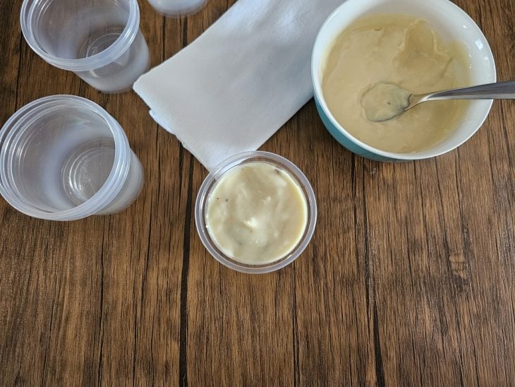 Um pote forrado com creme branco e coberto com pedaços de chocolate e mais creme.