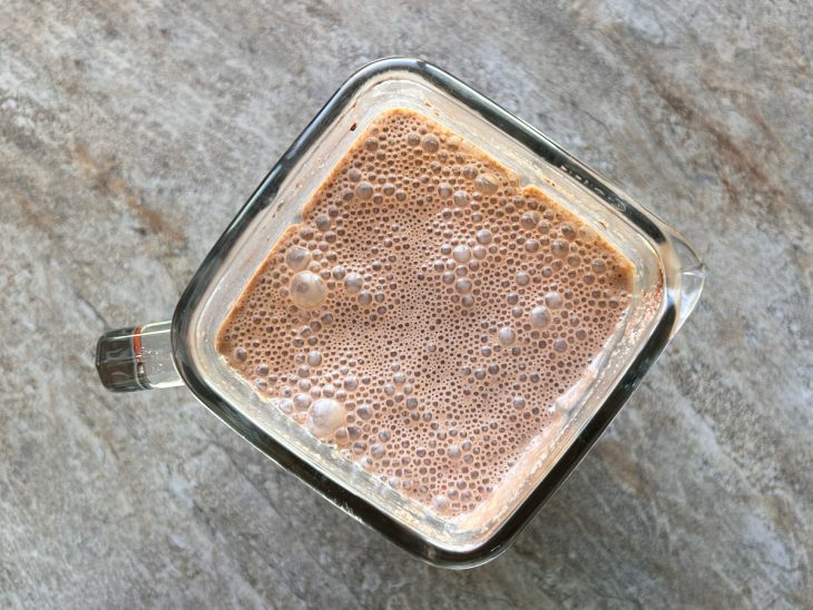 Ovos, leite condensado, manteiga, açúcar, cacau e leite batidos em um liquidificador.