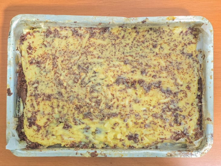 Bolo cortado e a camada do creme de coco adicionada sobre uma das partes.