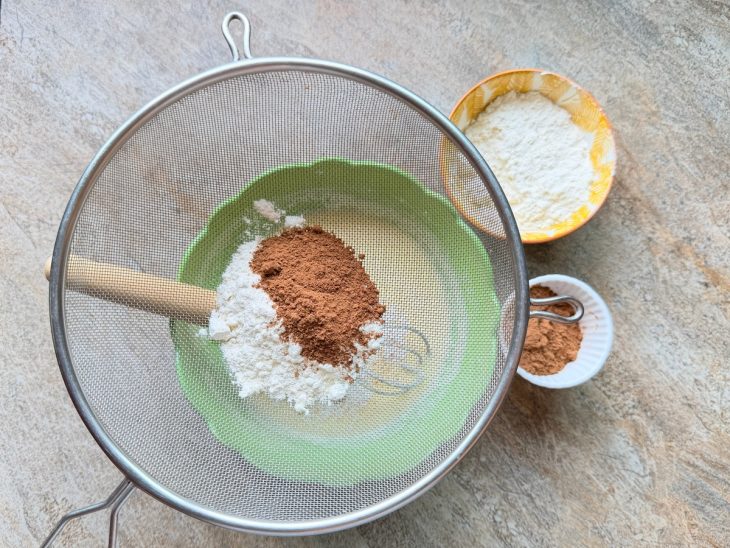 Chocolate em pó e farinha peneirados na tigela.