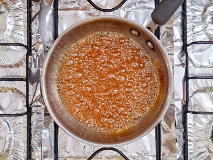 Açúcar sendo derretido em panela até formar caramelo e receber água para criar uma calda lisa.