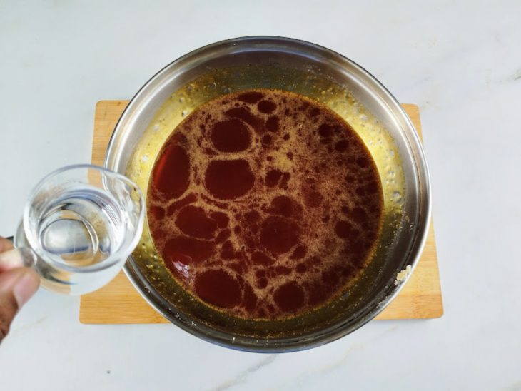 Água sendo despejada na panela com o caramelo.