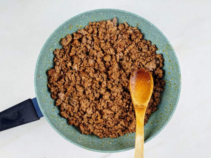 Carne moída temperada com sal e páprica em uma panela com azeite.