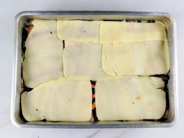 Rodelas de tomate e fatias de queijo mussarela adicionadas a forma.