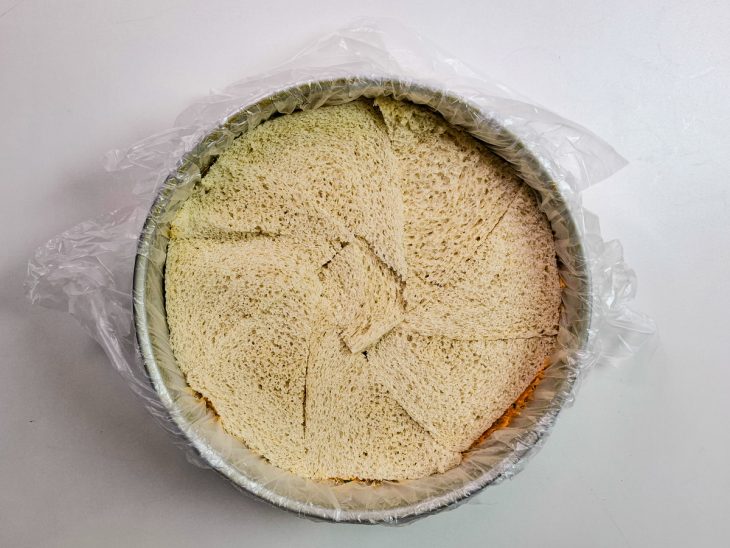 Camadas intercaladas de pão e recheio parta montagem de bolo salgado de frango.