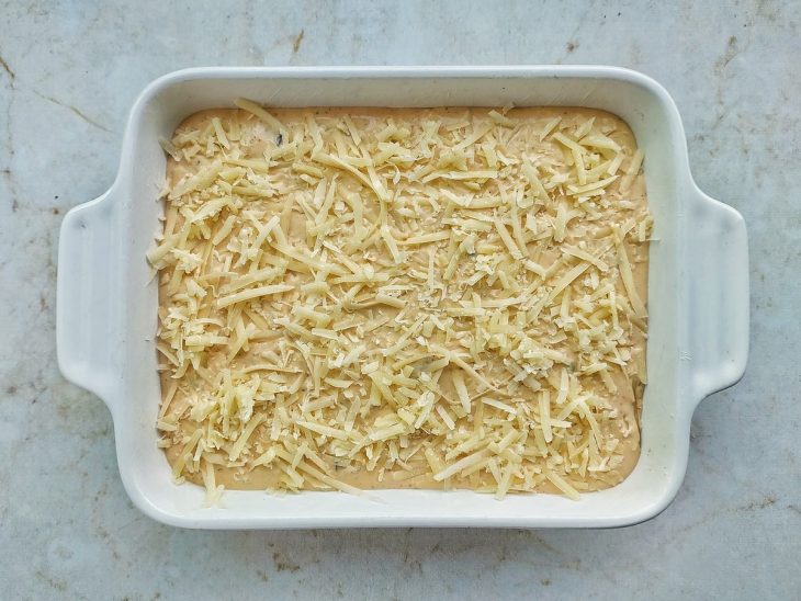Restante da massa e parmesão ralado adicionados por cima do recheio.