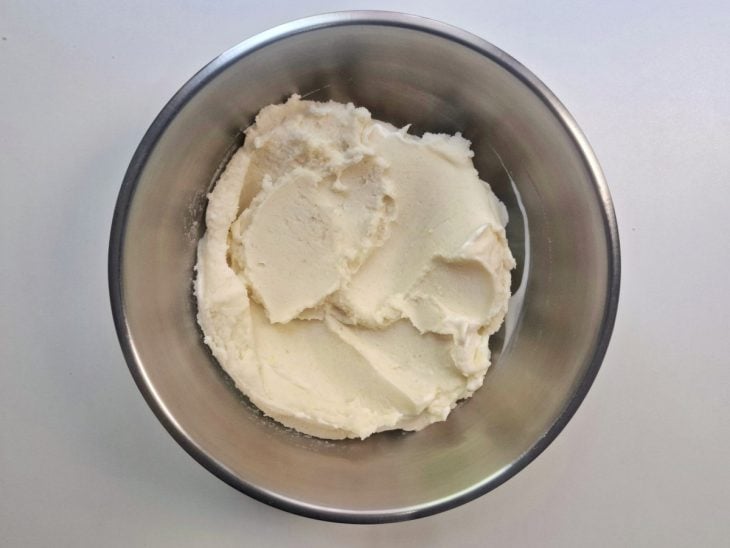 Batatas cozidas, creme de leite, sal e maionese misturados em um recipiente.