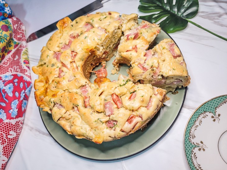 Bolo salgado de presunto e queijo com alguns pedaços cortados.