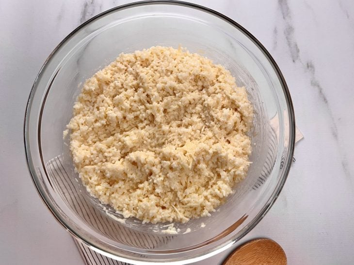 Um recipiente contendo a mistura de ovos batidos, manteiga, queijo parmesão, sal, tapioca e leite.