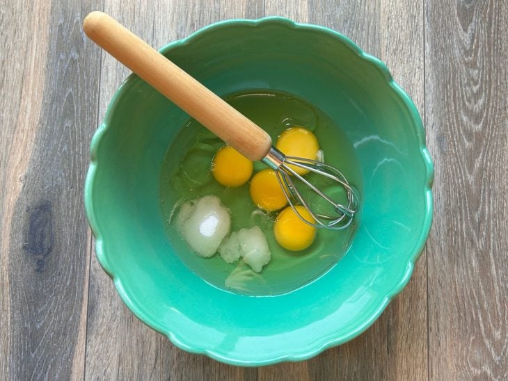 Ingredientes adicionados em uma tigela para bater com auxílio de um fouet.