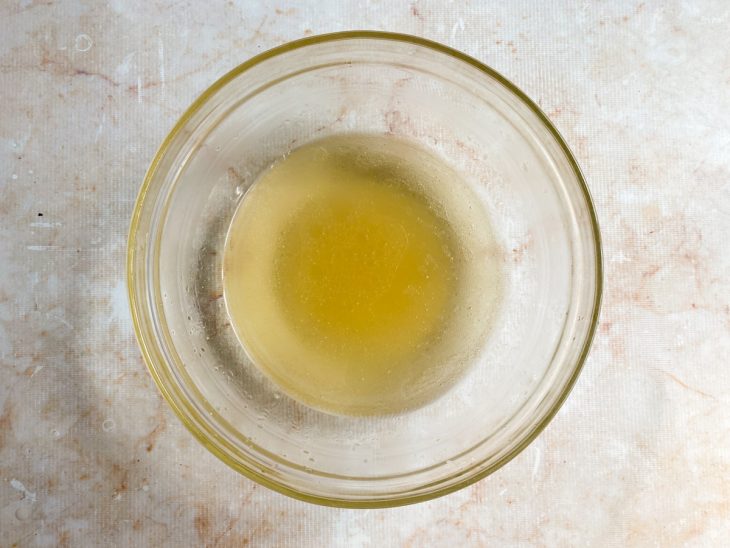 Açúcar misturada com óleo e água quente em uma tigela de vidro.