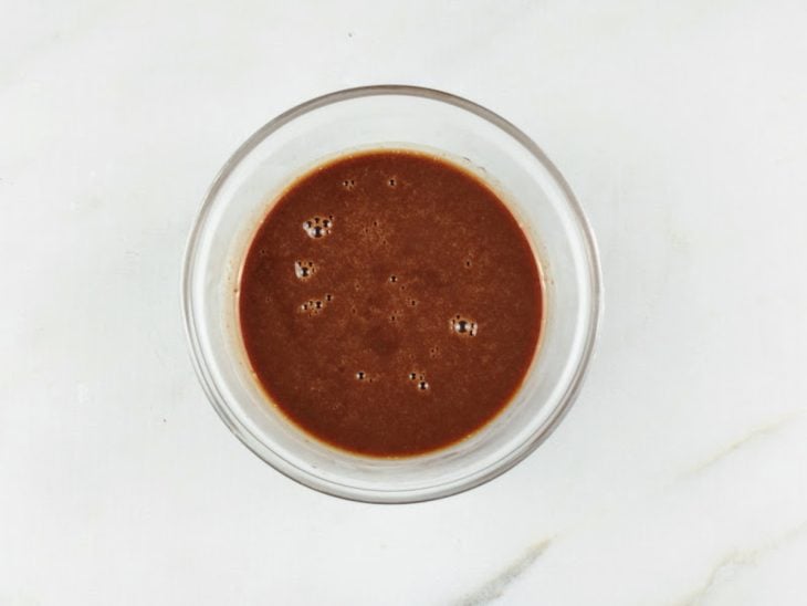 Chocolate derretido e misturado com creme de leite em uma tigela de vidro.