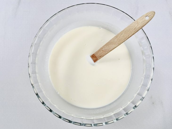 Numa tigela, o leite, o leite de coco e o leite condensado misturados.