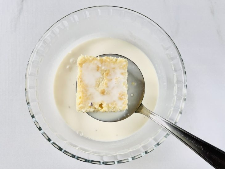 Pedaços do bolo sendo mergulhados na calda.