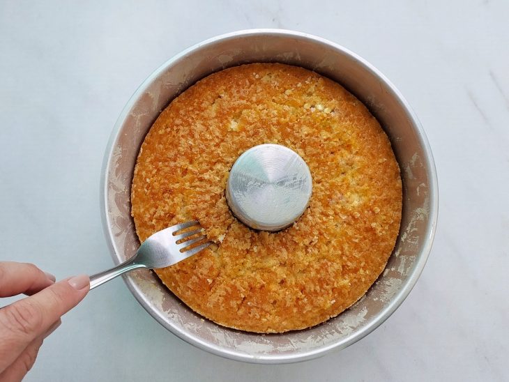 Bolo frio sendo furado com garfo para absorver a calda.