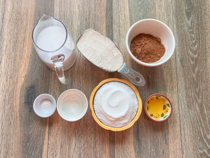 Ingredientes da receita em recipientes separados sobre uma superfície de madeira.