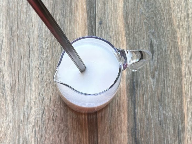 Leite de coco e vinagre misturados em um recipiente de vidro.