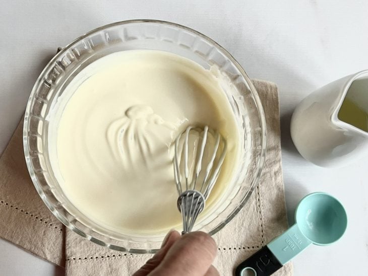 Suco de limão adicionado a mistura de creme de leite e leite condensado na tigela de vidro.