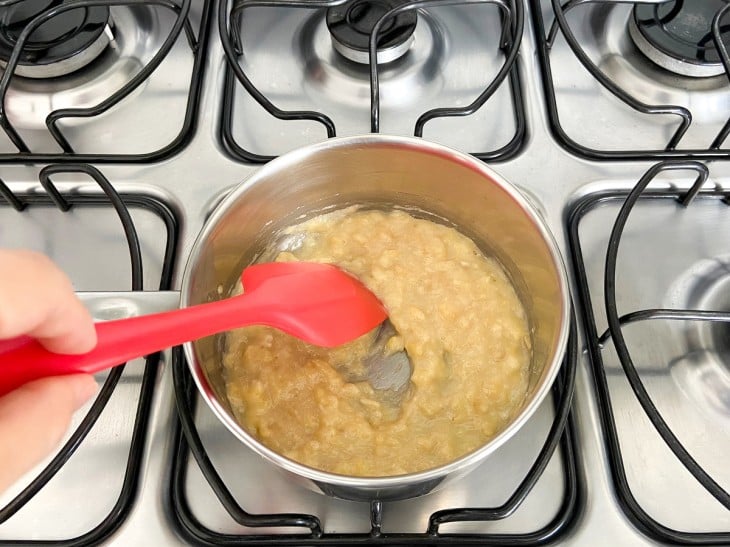 Uma panela contendo a mistura de bananas amassadas, mel e leite em pó.