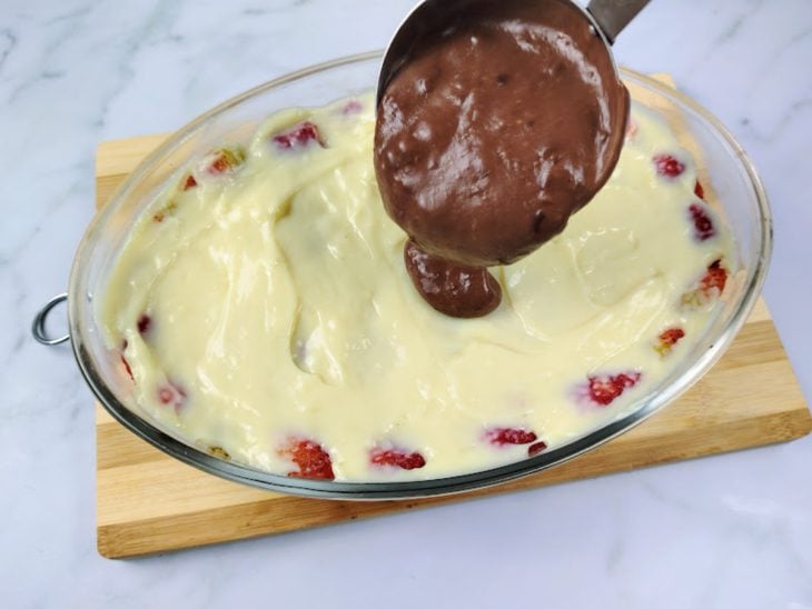 Uma travessa com uma camada de creme de leite ninho, morangos e ganache.