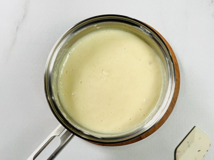 Leite em pó, leite condensado e creme de leite misturados em uma panela.