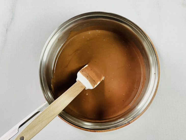 Chocolate meio amargo e creme de leite misturados em uma panela.