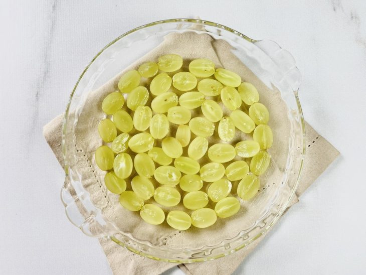 Uvas cortadas forrando um refratário de vidro.