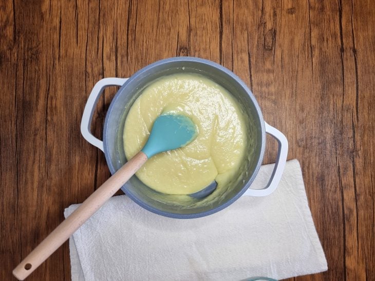 Ingredientes do creme branco em uma panela com uma espátula.