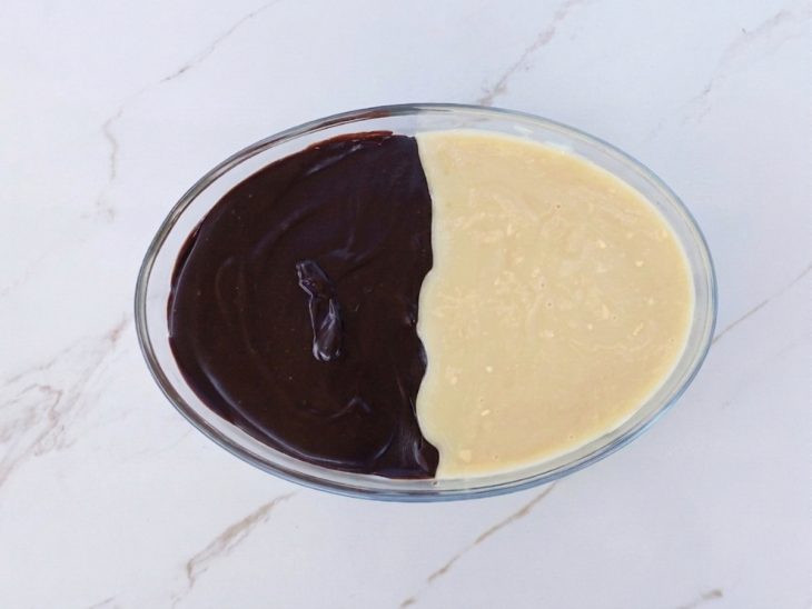 Cobertura de chocolate meio amargo e branco sendo distribuída sobre a sobremesa.