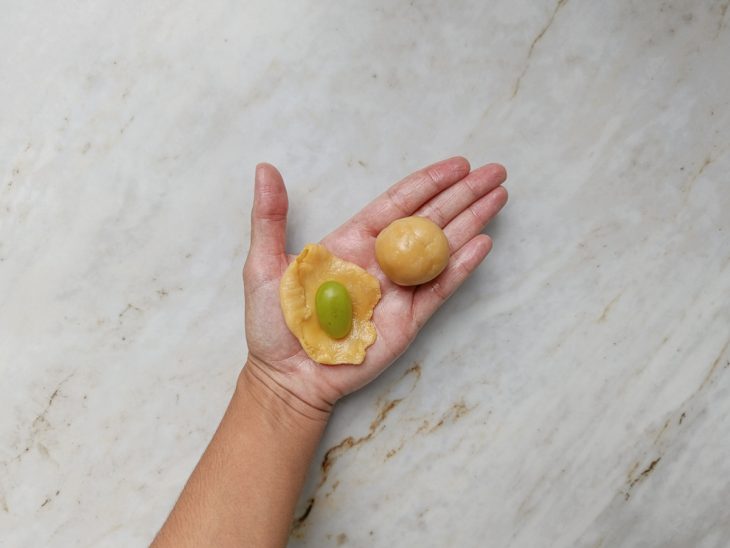 Porção de brigadeiro aberto, com uva no centro.