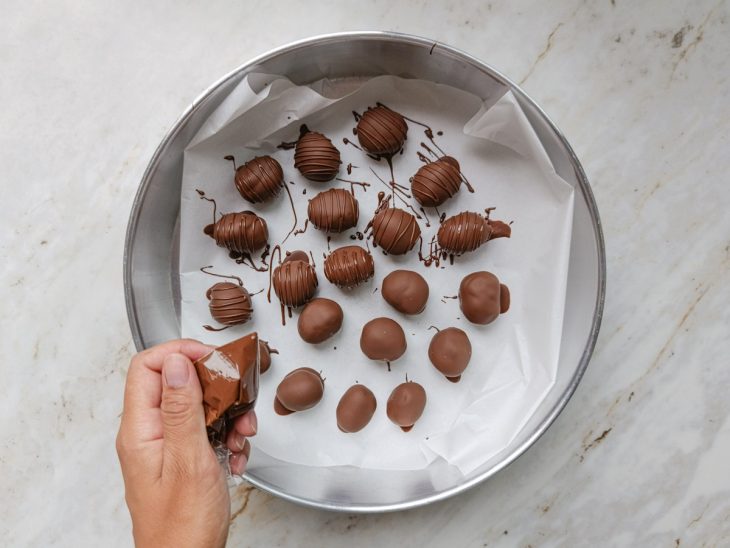 Bombons sendo decorados com o chocolate derretido.