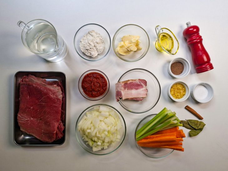 Ingredientes organizados na bancada com carne fatiada, legumes e temperos.