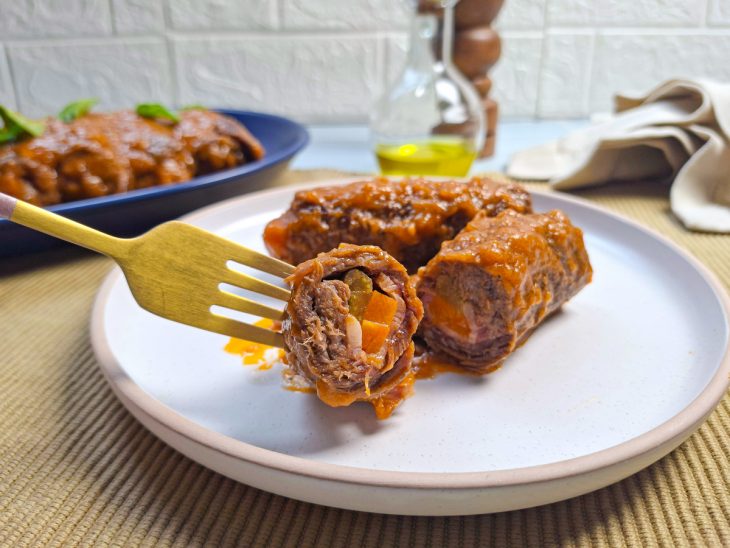 Bracciolas servidas na travessa cobertas com molho quente.