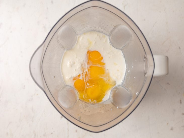 Ovos, leite condensado, creme de leite e leite fresco em um liquidificador.