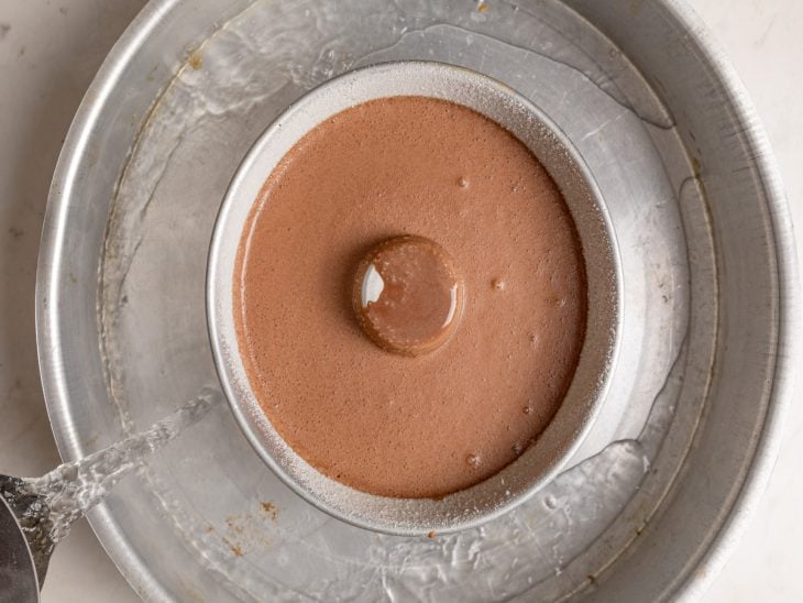 Forma com a mistura de brigadeirão sobre outra forma maior com água.