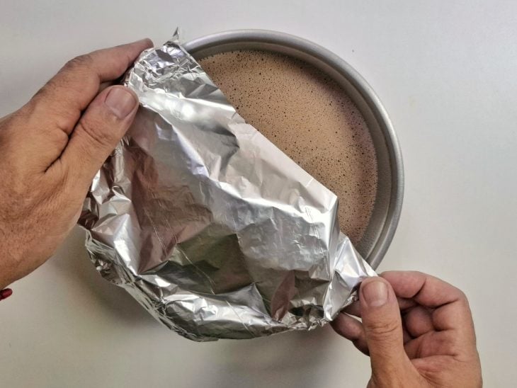 Mistura despejada na forma e coberta por papel-alumínio.