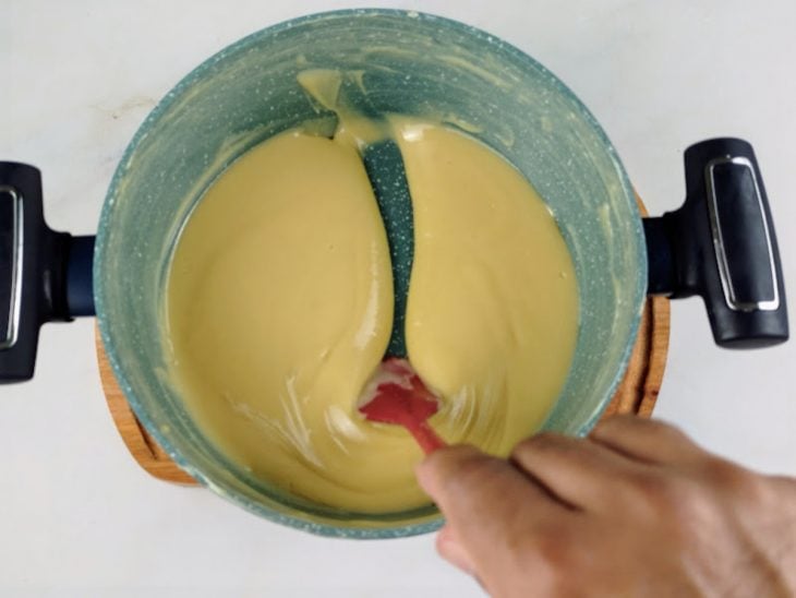 Leite condensado, creme de leite e manteiga misturados em uma panela.