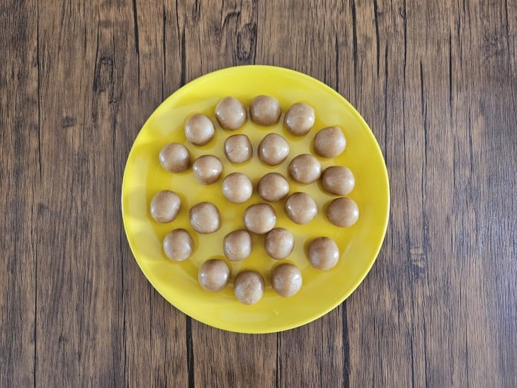 Um prato grande com vários brigadeiros de amendoins enrolados.
